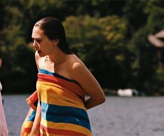 a woman in a colorful towel is standing by the water with her hand on her hip