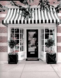 a black and white photo of a store front with awnings over the door