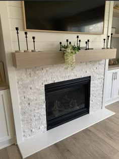 a fireplace with a tv above it and some candles on the mantels in front of it