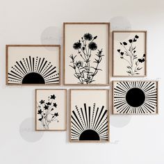 four black and white paintings hanging on the wall above a table with flowers in vases