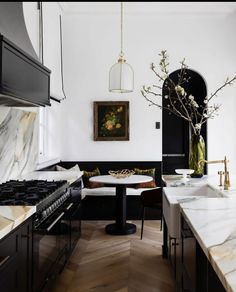 a kitchen with marble counter tops and black cabinets, along with an oval dining table