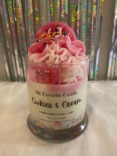 a glass jar filled with pink and white frosted cookies, sprinkles and candy