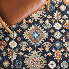 a brown leather chair sitting on top of a blue and orange rug with an ornate design