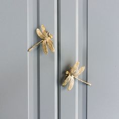 two gold dragonflys are mounted to the side of a gray painted cabinet door