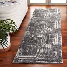 a gray rug on the floor in front of a window with potted plants next to it