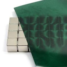 two metal cubes sitting next to each other on top of a green piece of paper