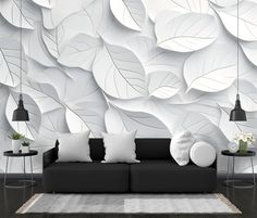 a black and white living room with large wall paper leaves on the wall behind it