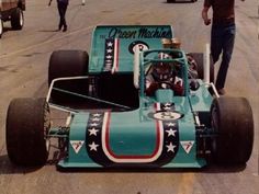 a blue race car with stars and stripes on it's side, sitting in the middle of a street