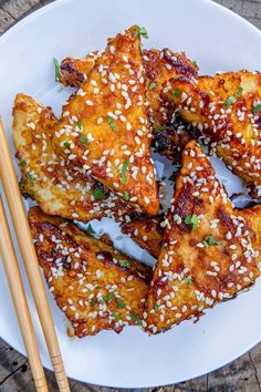 chicken wings with sesame seeds and chopsticks on a white plate