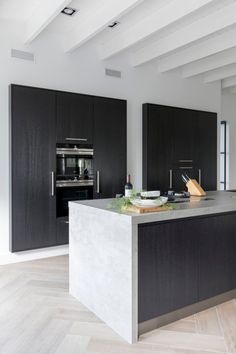 a large kitchen with black cabinets and an island in the middle of the room is shown