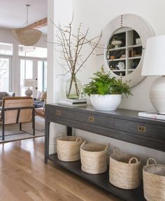 a table with baskets and plants on it in a living room next to a couch