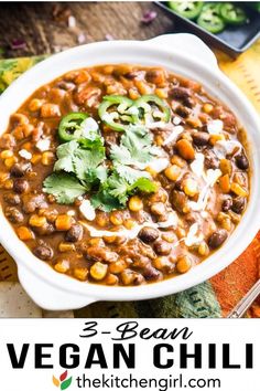 three bean vegan chili in a white bowl with cilantro and green garnish