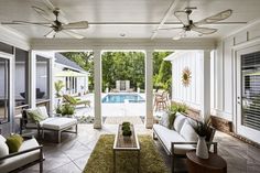 an outdoor living area with couches, tables and ceiling fans