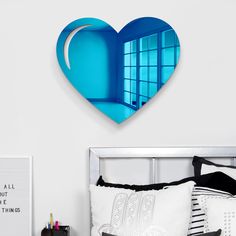 a heart shaped mirror on the wall above a bed