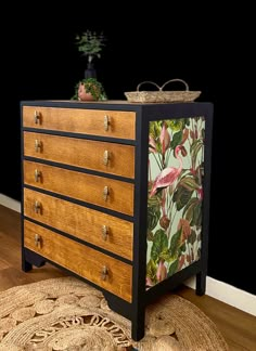 a wooden dresser with tropical print on the front and drawers, next to a potted plant