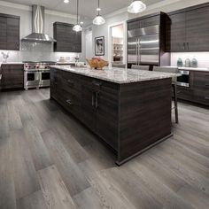 a large kitchen with wooden floors and stainless steel appliances in the center, along with dark wood cabinetry