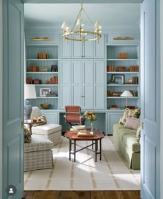 a living room filled with furniture and bookshelves next to a doorway that leads to a sitting area