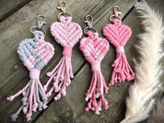 three crocheted heart keychains with tassels are on a wooden surface