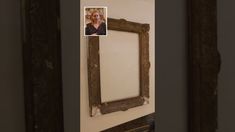 an old wooden frame hanging on the wall with a woman's face reflected in it