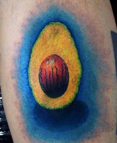 an avocado tattoo on the leg with blue and yellow ink around it's center