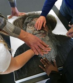 a group of people standing around each other with their hands on a piece of metal