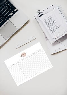 an open laptop computer sitting on top of a desk next to a notepad and pen