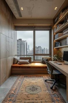 a room with a couch, desk and bookcases in front of a large window