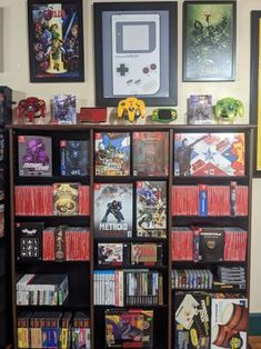 a bookcase filled with video games next to pictures on the wall