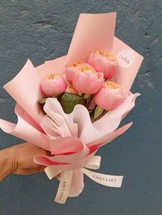 a hand holding a bouquet of pink flowers