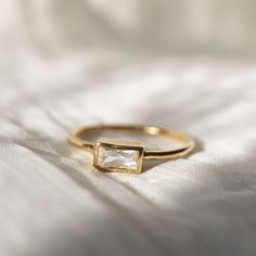 a close up of a gold ring with a white diamond in it on a bed