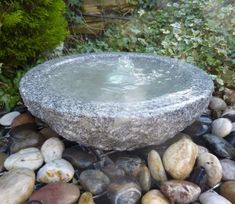 a stone fountain surrounded by rocks and gravel