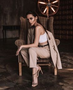 a woman is sitting in a chair with her legs crossed and wearing high heeled sandals