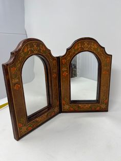 an ornate wooden mirror with two mirrors on it's sides and one in the middle