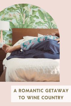 a woman laying on top of a bed next to a night stand with a lamp