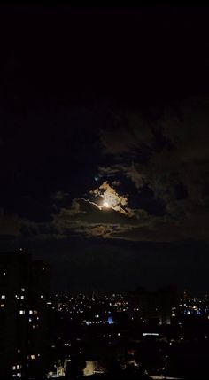 the moon is shining brightly in the dark night sky over city lights and skyscrapers