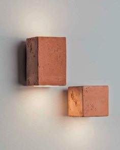 two brick lights are on the wall in front of a gray background and one is lit up