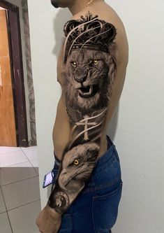 a man with a lion and cross tattoo on his arm is standing in front of a wall