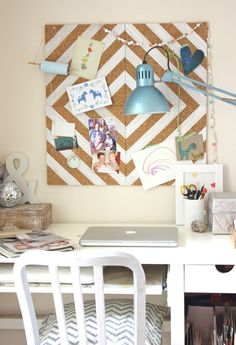 a desk with a laptop computer on top of it in front of a wall decorated with pictures