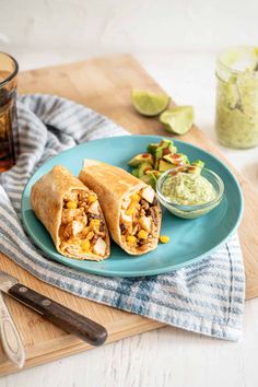 two burritos are on a blue plate with guacamole and salsa