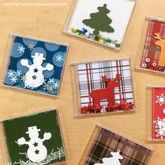 four different christmas cards in plastic cases sitting on a table with snowmen and reindeer