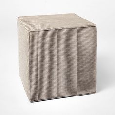 a small square stool with a checkered pattern on the top and bottom, sitting in front of a white background