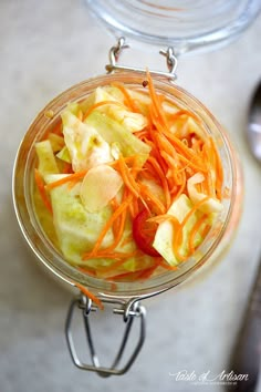 a glass bowl filled with sliced vegetables on top of a table next to a spoon