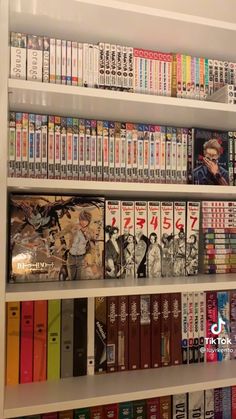 a book shelf filled with lots of books on top of white shelves next to each other