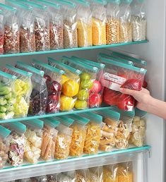 a person is picking up some food from the freezer and it's packed with plastic bags