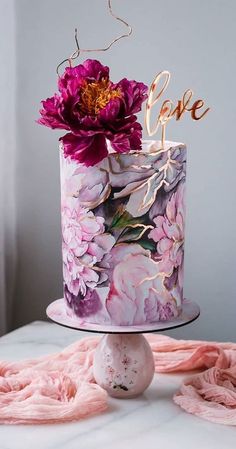 a cake decorated with flowers and the word love on top is sitting on a table