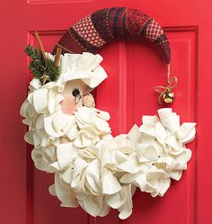 a red door with a wreath on it and a santa clause head hanging from the front