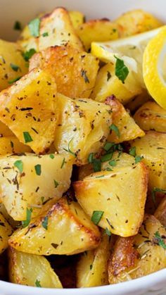 a white bowl filled with potatoes and lemon wedges