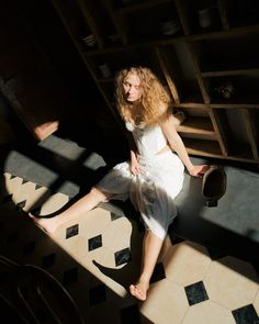 a woman in a white dress sitting on the floor