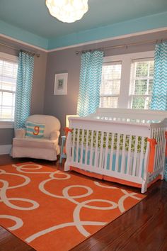 a baby's room with blue and orange curtains, a white crib and a chair