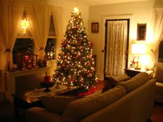 a living room with a christmas tree in the corner and lights on it's walls